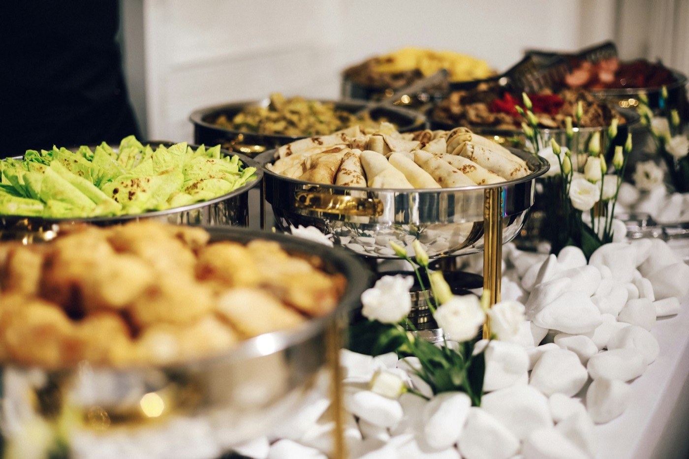 Catering buffet with chafing dishes of rolled crepes and salads